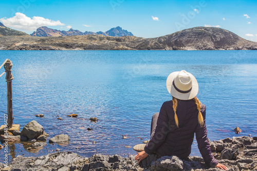 Beautiful woman sitting on the shore of the lake in front of the Pastoruri glacier, in the Huascaran National Park, Huaraz / Peru. photo