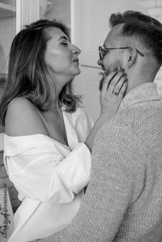 Beautiful young couple is talking and smiling in kitchen at home. 