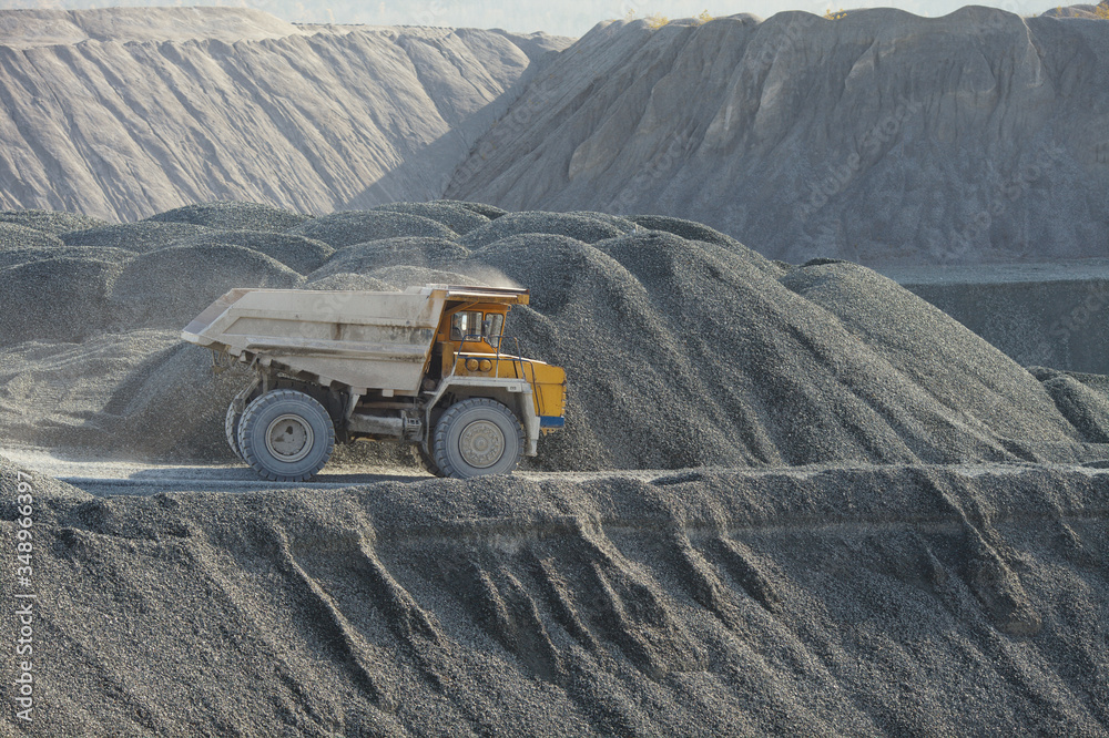 Mining dump truck on the background of bulk hills of crushed stone, close-up. Mining industry. Mining dump truck on the background of bulk hills of crushed stone, close-up. Mining industry.