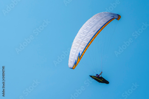 White glider with the pilot on the background of blue sky. Side view. Copy space.