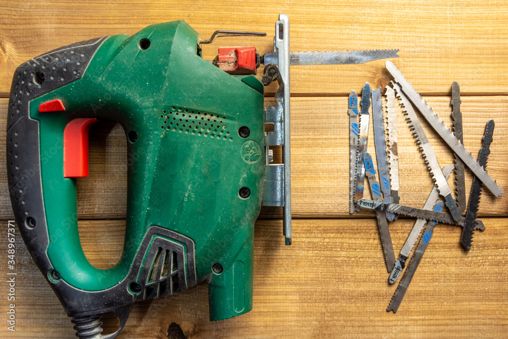 Electric jigsaw and jigsaw files on a wooden background. Top view