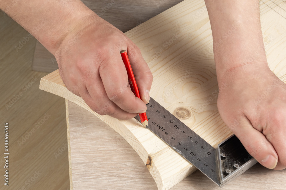 The craftsman marks the wooden board with a ruler and pencil. Carpentry workshop. Work carpenter The craftsman marks the wooden board with a ruler and pencil. Carpentry workshop. Work carpenter