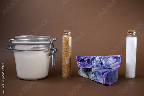 Hand made soaps, body cream or lotion, salt and sugar on the brown background. Natural cosmetics. Small business. Copy space.