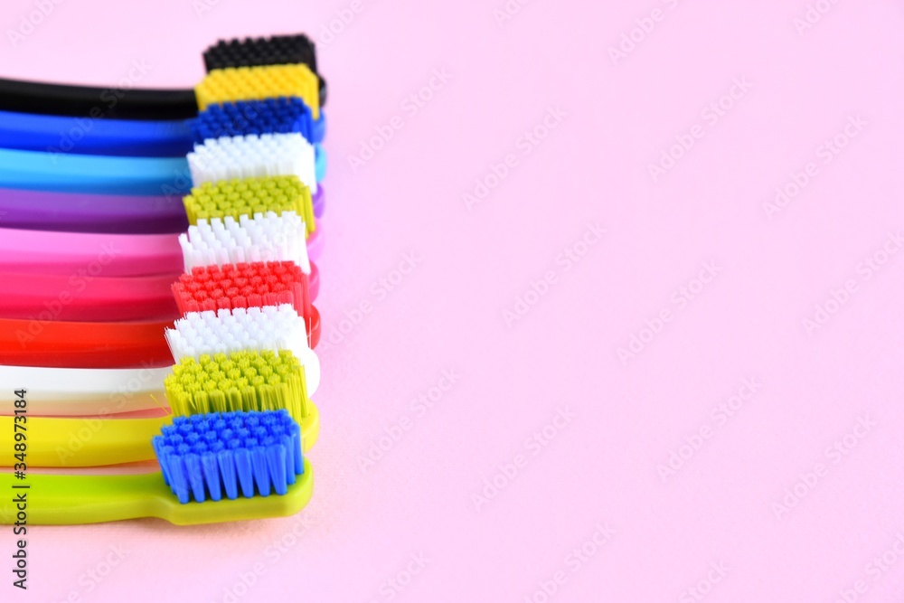 Row of bright colorful toothbrushes with selective focus on pink background. Healthy teeth. Toothbrush for daily oral care Row of bright colorful toothbrushes with selective focus on pink background. Healthy teeth. Toothbrush for daily oral care