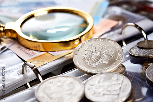 Silver dollar and numismatic coins with magnifying glass photo