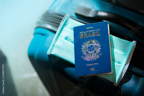 Mala de viagem, passaporte brasileiro e máscara de proteção. A proibição e as novas medidas de viajar durante a epidemia do coronavírus. photo