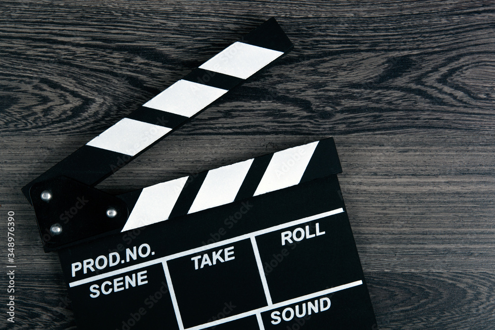 Obraz premium black movie clapper with white inscriptions on a wooden table