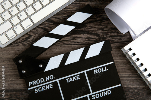 Bilde på lerret black movie clapper with keyboard and script sheets on a wooden table