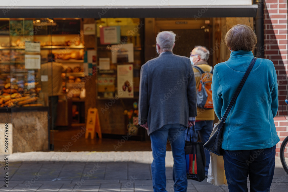 Selected focus view, Group of European people queue and wait for buy food on sidewalk outside store during social distancing and quarantine regulations for COVID-19 virus in Düsseldorf, Germany. Selected focus view, Group of European people queue and wait for buy food on sidewalk outside store during social distancing and quarantine regulations for COVID-19 virus in Düsseldorf, Germany.