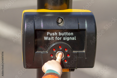 Tiny little hand of a toddler pushing the button on the traffic light control  photo