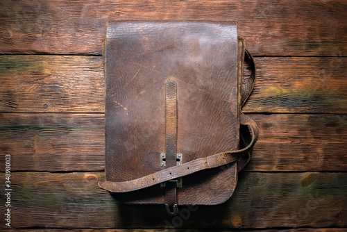Old retro brown leather bag on the table flat lay background.