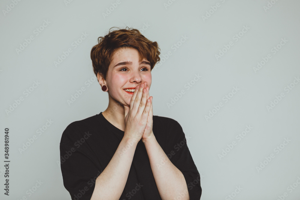 A girl with short hair stands on a white background and smiles A girl with short hair stands on a white background and smiles