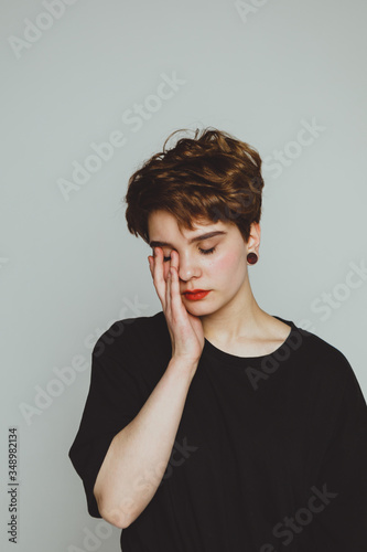 Fotografie Girl with short hair cries on a white background
