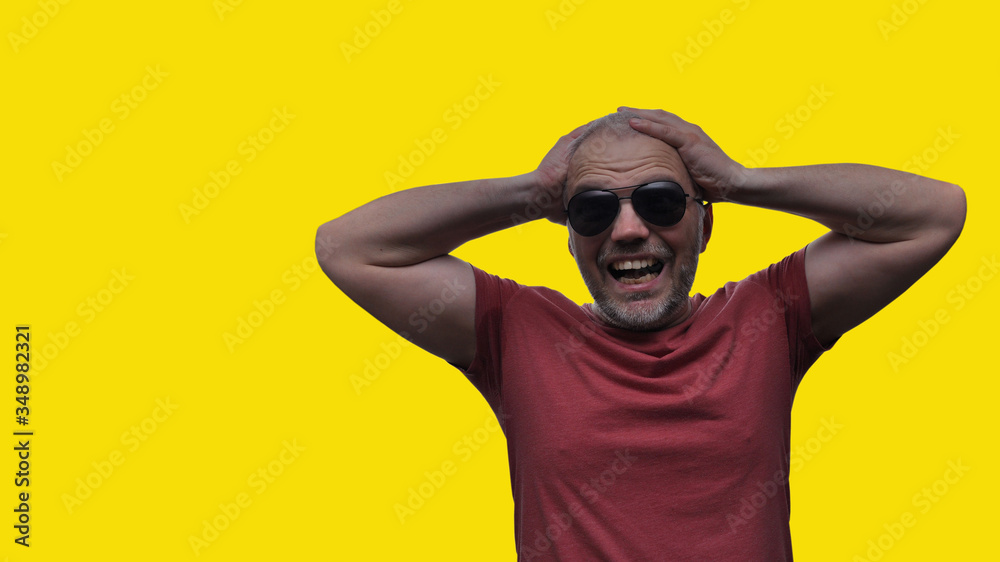 The man holds his hands behind his head and screams from despair and disappointment, his eyes are full of horror, his mouth opened. The man holds his hands behind his head and screams from despair and disappointment, his eyes are full of horror, his mouth opened.