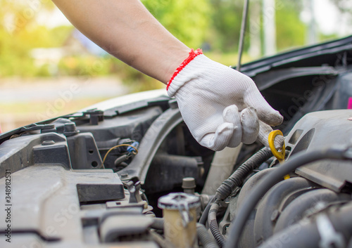 Mechanic's hands check or fix the engine oil check point of the engine.