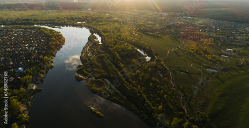 Fototapeta Naklejka Na Ścianę i Meble -  Panoramic aerial view of the nature landscape with green meadows and a river at sunset.