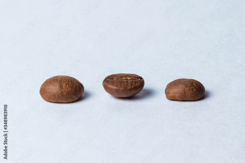 Fototapeta premium Three coffee beans stand in a row on a white background
