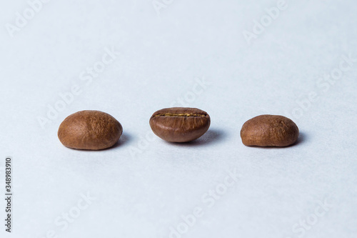 Three coffee beans stand in a row on a white background