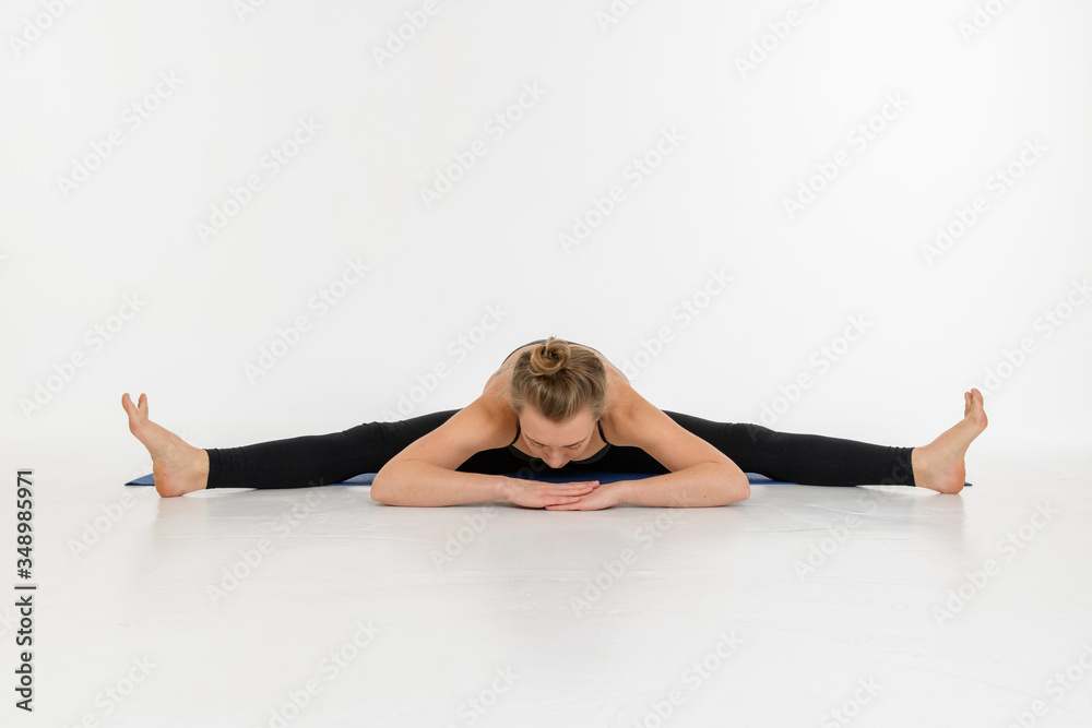 Sporty attractive young woman doing yoga practice on white background. Upavistha Konasana.