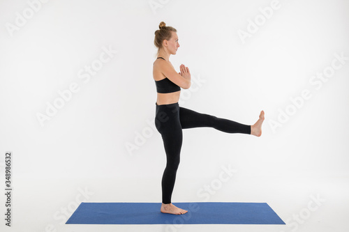 Sporty attractive young woman doing yoga practice on white background. © Alexey Seafarer