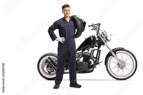 Mechanic carrying a tire and standing next to a chopper motorbike