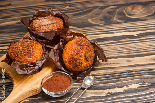 Homemade delicious muffins ith cacao on wooden background close-up