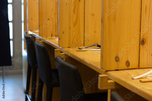 Selective focus of empty black chairs, wooden tables and partitions in a Japanese restaurant. Interiors design by wood.