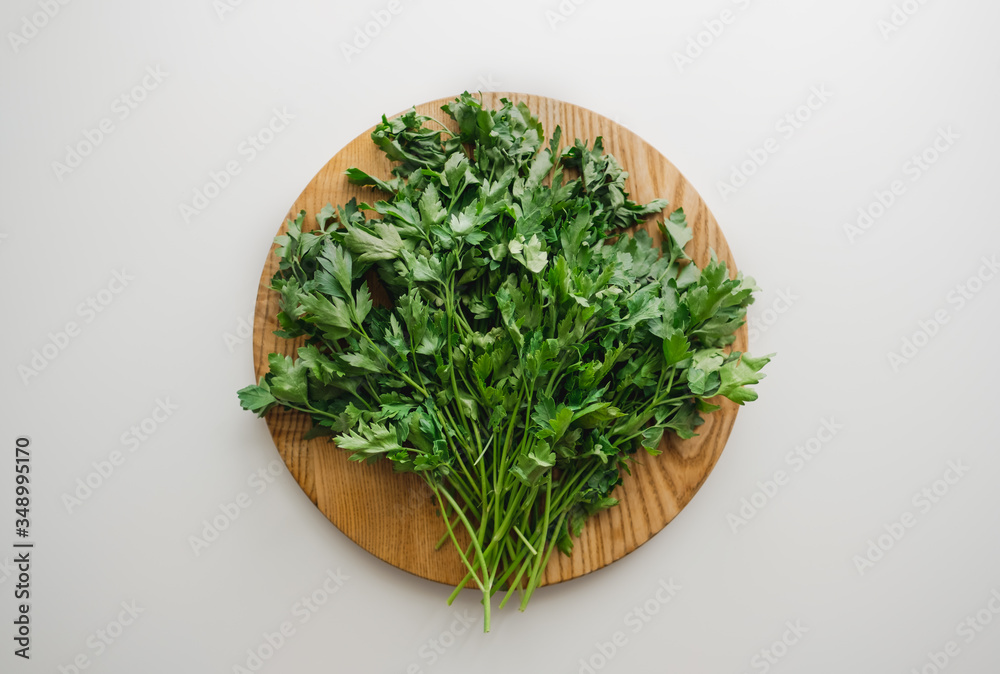Green parsley on a wooden board, white background. Proper nutrition. Flat lay Green parsley on a wooden board, white background. Proper nutrition. Flat lay
