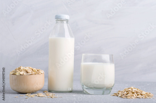 oat milk, gluten-free vegetarian organic milk, a glass bottle and a glass of oat milk on a gray background