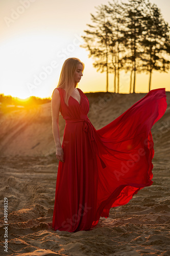 Beautiful fashion girl among the sands at sunrise