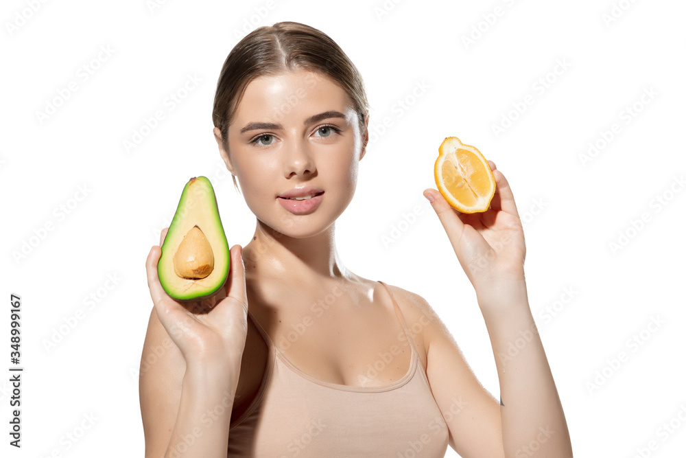Portrait of beautiful young woman with avocado and orange over white background. Concept of cosmetics, makeup, natural and eco treatment, skin care. Shiny and healthy skin, fashion, healthcare. Portrait of beautiful young woman with avocado and orange over white background. Concept of cosmetics, makeup, natural and eco treatment, skin care. Shiny and healthy skin, fashion, healthcare.