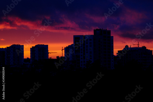 Beautiful sunset in the city. Silhouette of houses and construction cranes. Selective focus.