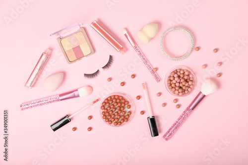 Set of decorative cosmetics and accessories on a pink background.