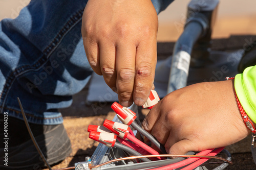 A technician attaches wire nuts to a series of red grey and black wires in an electrical box. photo