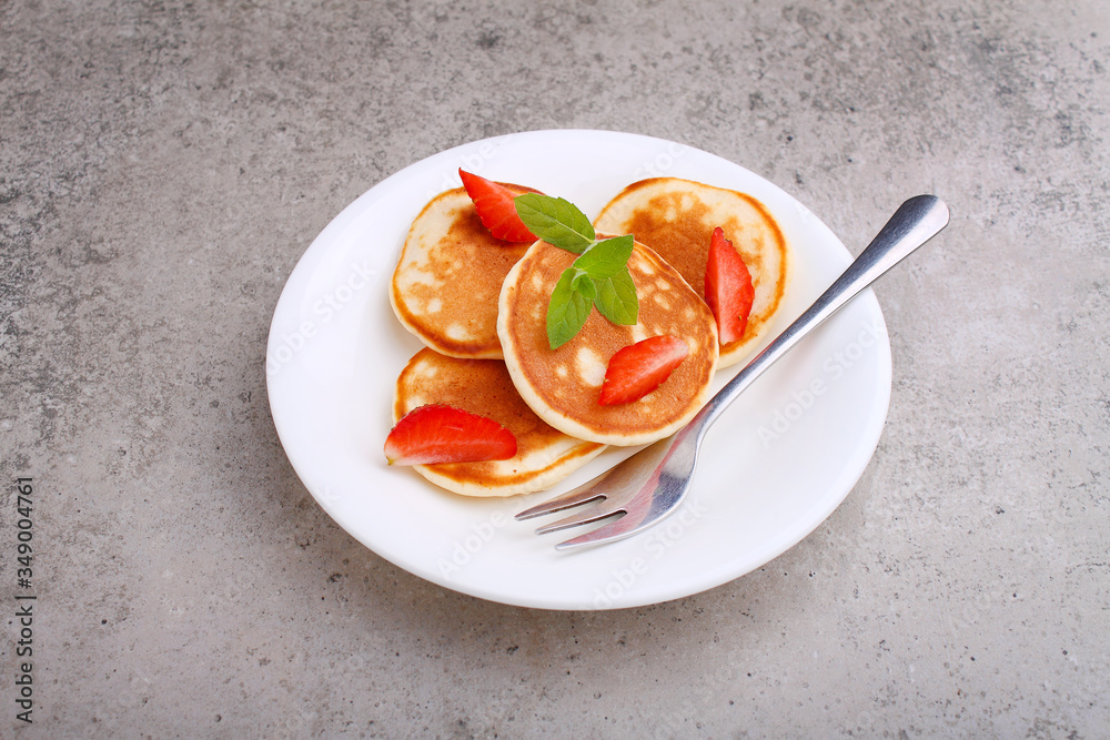 Pancake in a plate with strawberries decorated with mint on a concrete background Pancake in a plate with strawberries decorated with mint on a concrete background