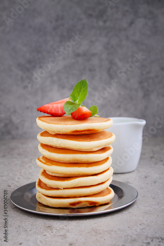 Pancake in a plate with strawberries decorated with mint on a concrete background