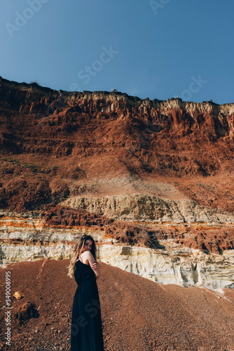 Girl in a black dress on the ocean near the cliff.