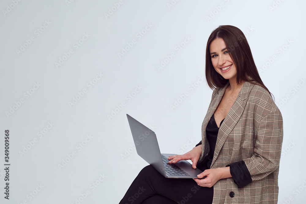 attractive business woman in a jacket sitting with a laptop and smiling attractive business woman in a jacket sitting with a laptop and smiling
