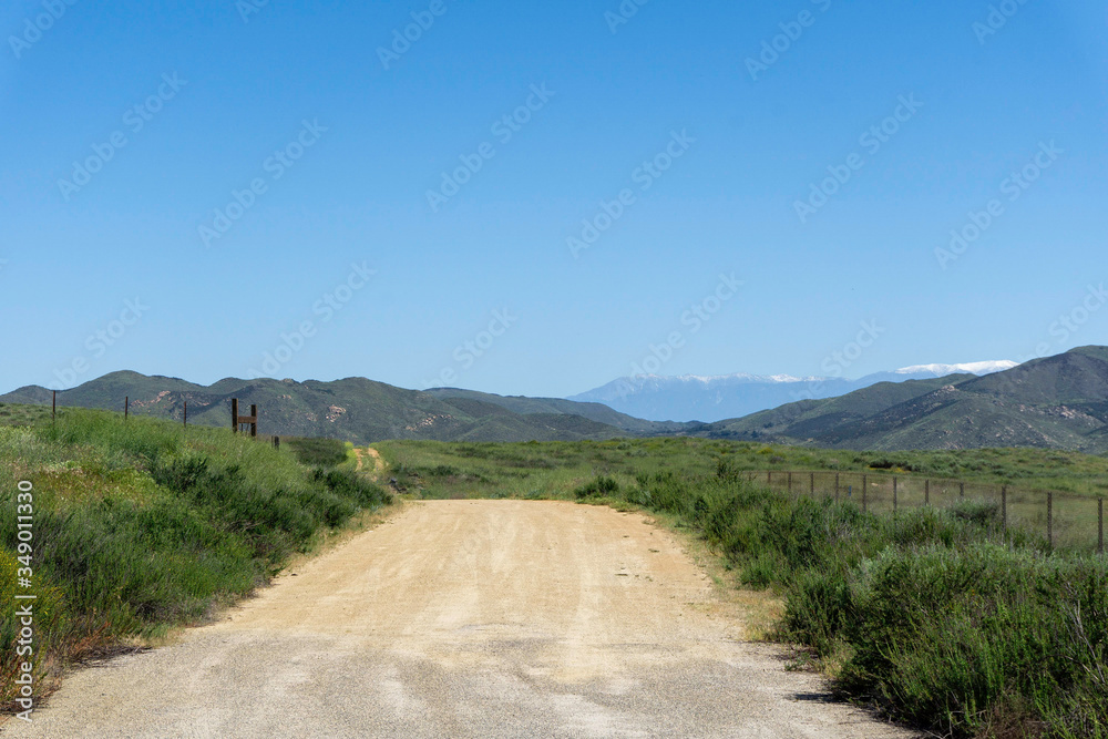 Dirt road in the country with snow capped mountains in the distance Dirt road in the country with snow capped mountains in the distance