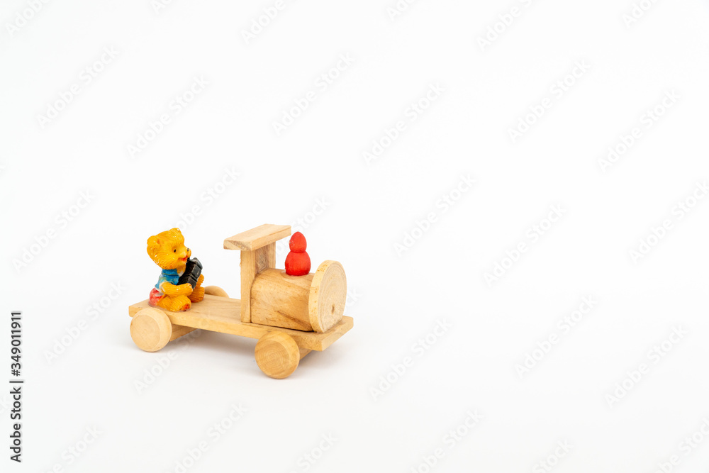 Wooden train on a white background. Wooden toy yellow locomotive with a teddy bear.