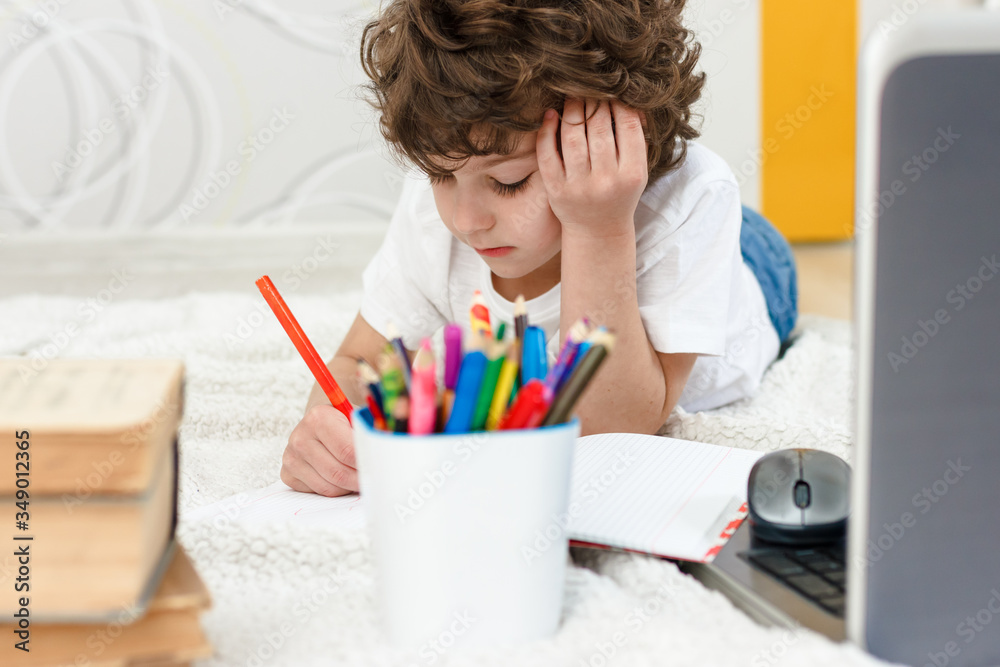Curly Tired child does homework. Concept of difficulties of home schooling, distance studying Curly Tired child does homework. Concept of difficulties of home schooling, distance studying