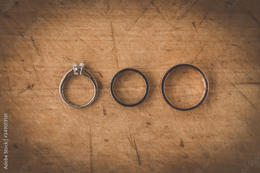 Wedding and engagement rings on a textured wooden Board. Wedding and engagement rings on a textured wooden Board.