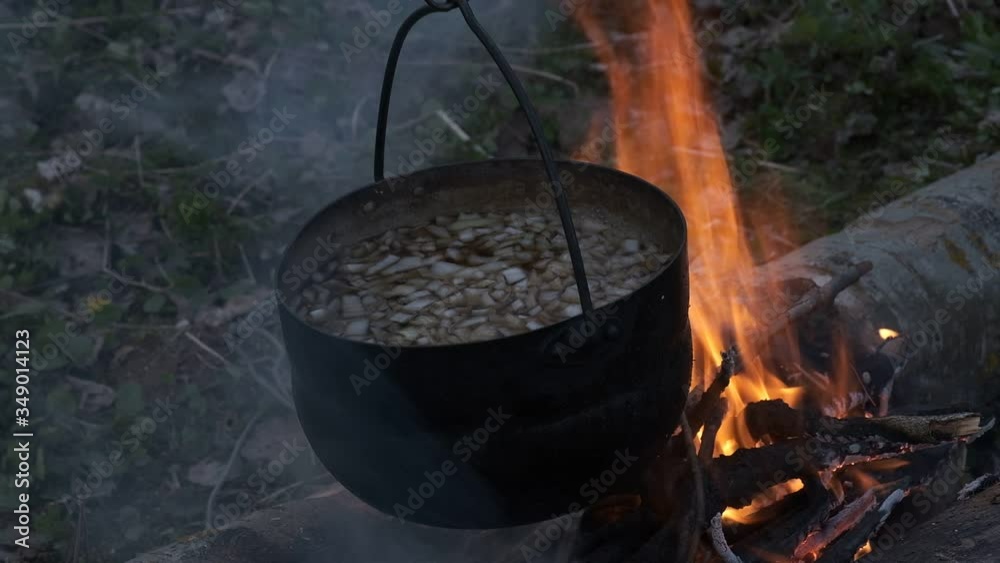 Food is cooked in black pot at the stake. Food is cooked in black pot at the stake.