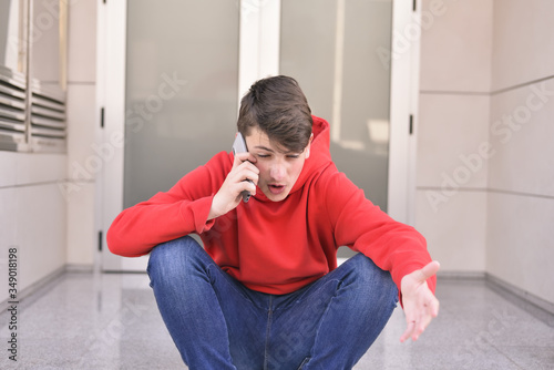 worried young man talking on his smarthphone sitting on the sidewalk