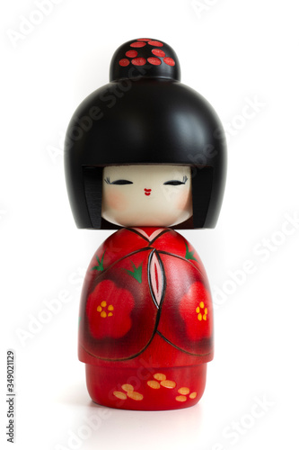 Kokeshi doll in red kimono. Still-life photo (taken on studio with white background and softbox) of a Japanese traditional doll isolated on white.