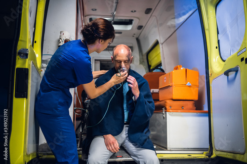 A young nurse in a uniform gives an oxygen mask to a man rescued from the fire