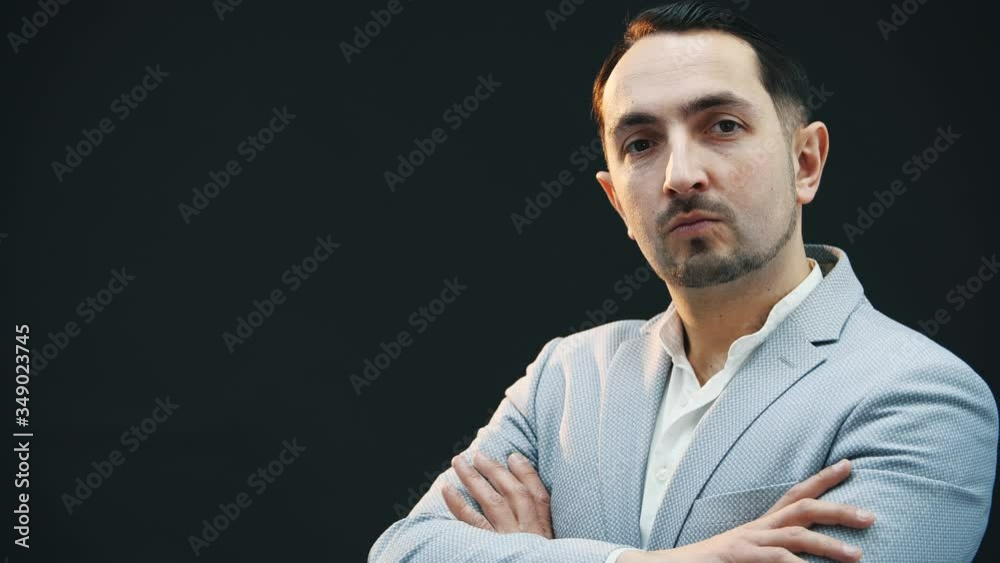 Serious young concentrated man standing in profile, his hands folded, then looking at the camera, posing. Serious young concentrated man standing in profile, his hands folded, then looking at the camera, posing.