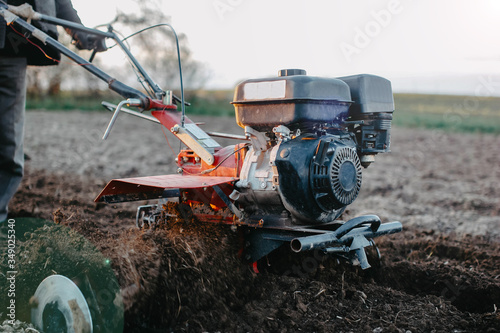 Fototapeta Naklejka Na Ścianę i Meble -  tractor motoblock works in the field at sunset. cultivates the soil.