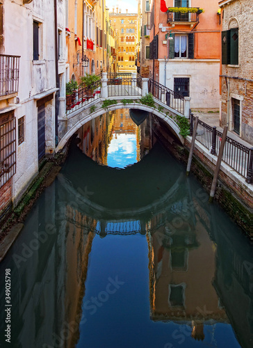 Tourist view of Venice. Channels with reflections. Street lights and colorful houses in the bright sun. Comfort and tranquility.