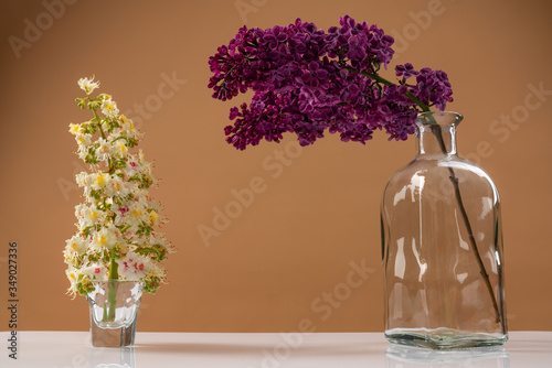 Bouquet of beautiful spring flowers of lilac in a glass and vase on a white wooden board, home decor in a rustic style